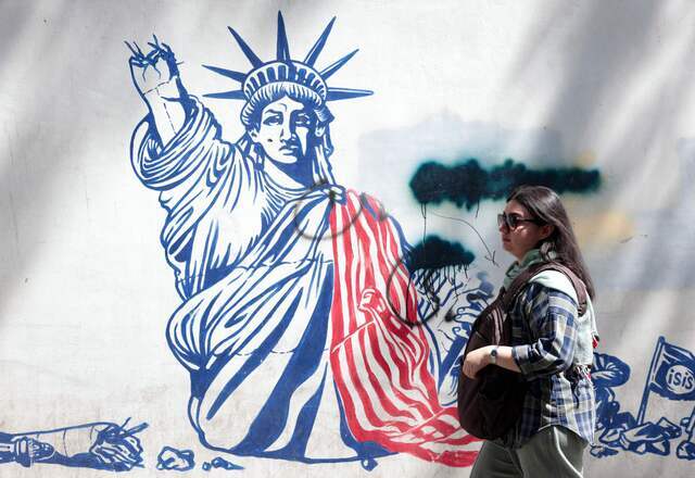 A woman walks next to an anti-US mural near the former US embassy in Tehran May 11, 2025.  (AFP photo)